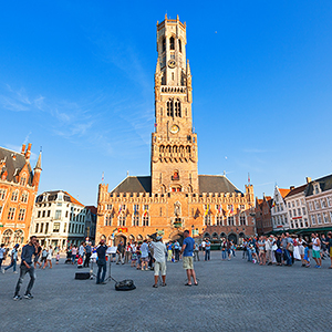 Bruges, Belgium, groups of people enjoying street musicians in The Markt place (Market square), with the Belfort as background (Jose Ignacio Soto / Shutterstock.com)