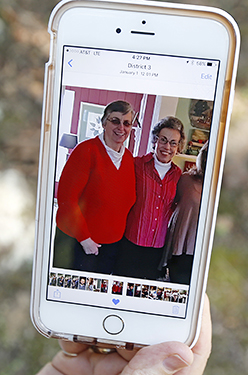 Jamie Sample, a parishioner of St. Thomas the Apostle Catholic Church in Lexington, Miss., sits in the shade in Durant, Miss., and shows a smartphone photograph taken last December 2015, of Sisters Paula Merrill, left, and Margaret Held. The two nuns who worked as nurses, and lived in Durant, Miss., were found slain in their home Thursday, Aug. 25, 2016. There were signs of a break-in and their vehicle was missing. (Courtesy Sample family via AP)