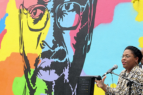Jennifer Pinckney speaks beside an image of her late husband, the Rev. Clementa Pinckney, one of the victims of the shootings at Charleston's Emanuel AME Church, during the unveiling of the mural on a building a few blocks from the sanctuary on Friday, May 13, 2016. The mural was created by artist Tripp Derrick Barnes to honor the nine shooting victims as the first anniversary of the June 2015 slayings approaches. (AP Photo/Bruce Smith)